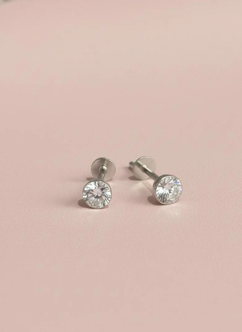 Pair of stone stud earrings on a pink background