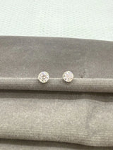 Two stone stud earrings on a gray fabric surface