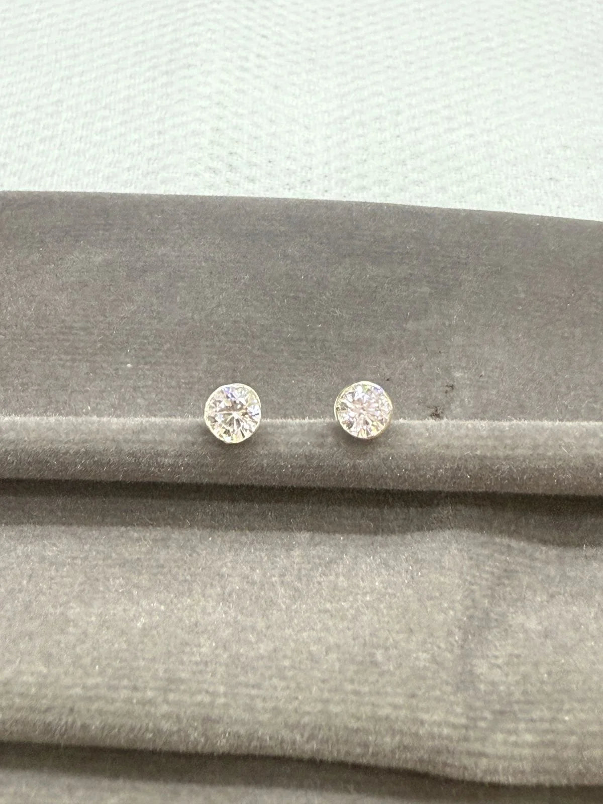 Two stone stud earrings on a gray fabric surface