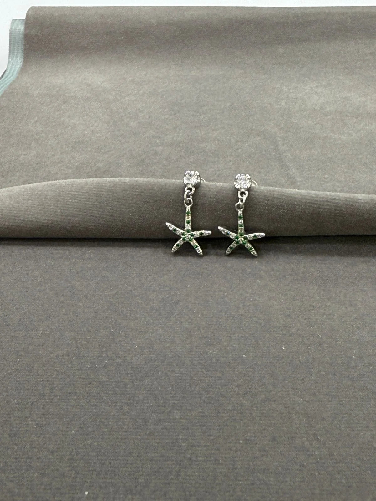 Starfish-shaped earrings on a gray surface