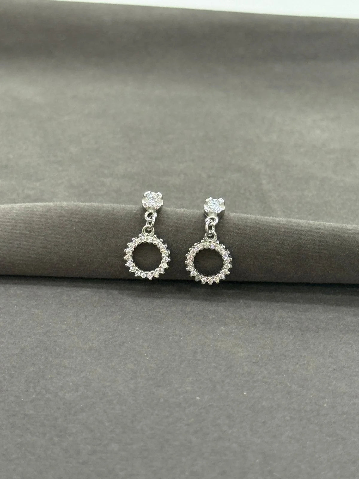 Silver earrings with circular design on a gray surface