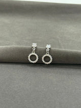 Silver earrings with circular design on a gray surface
