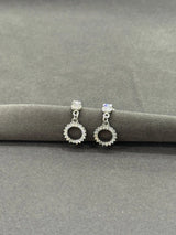 Pair of silver earrings with gemstones on a gray surface