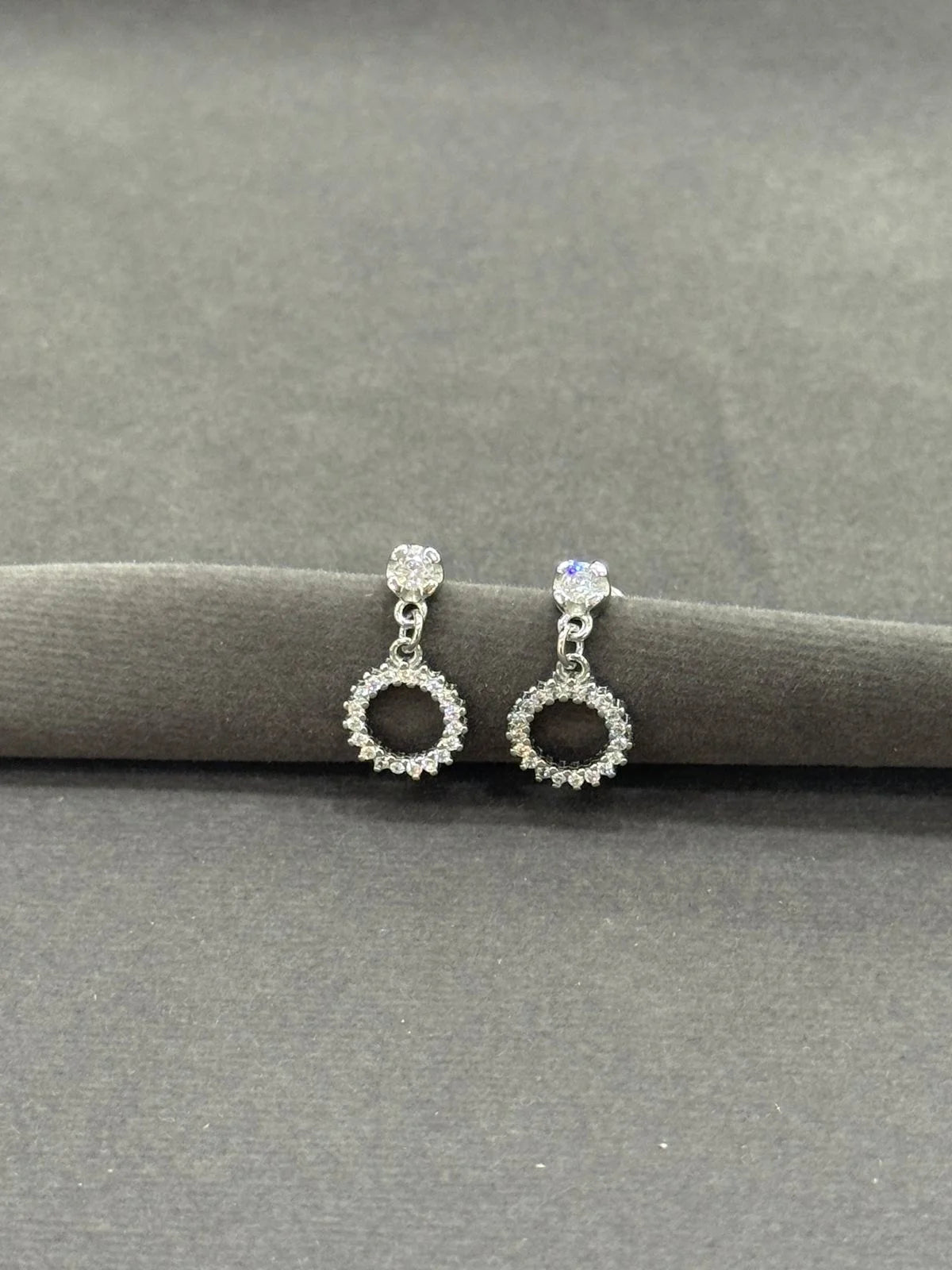 Pair of silver earrings with gemstones on a gray surface