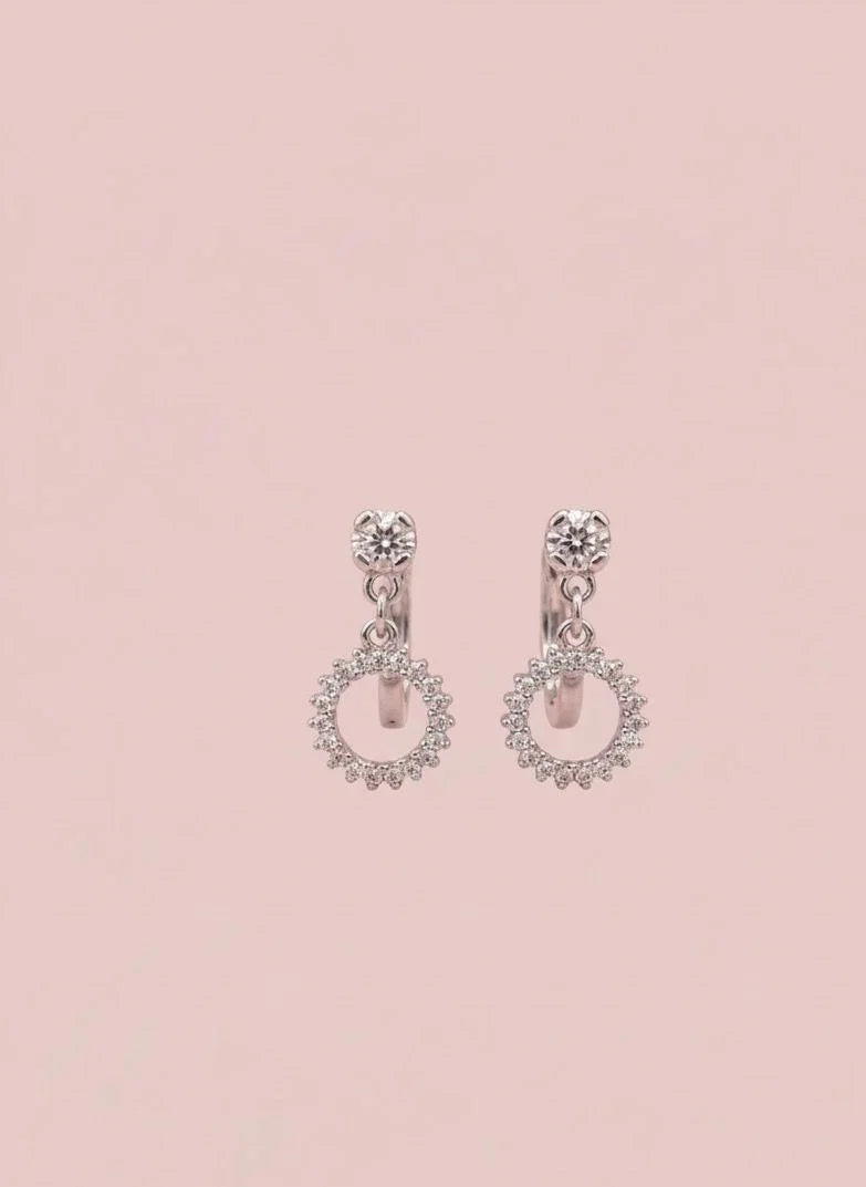 Pair of silver earrings with pink gemstones on a light pink background