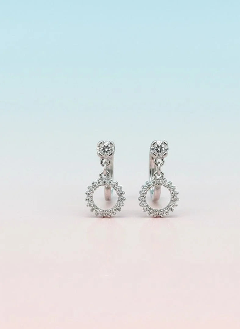 Pair of silver earrings with circular designs on a gradient background