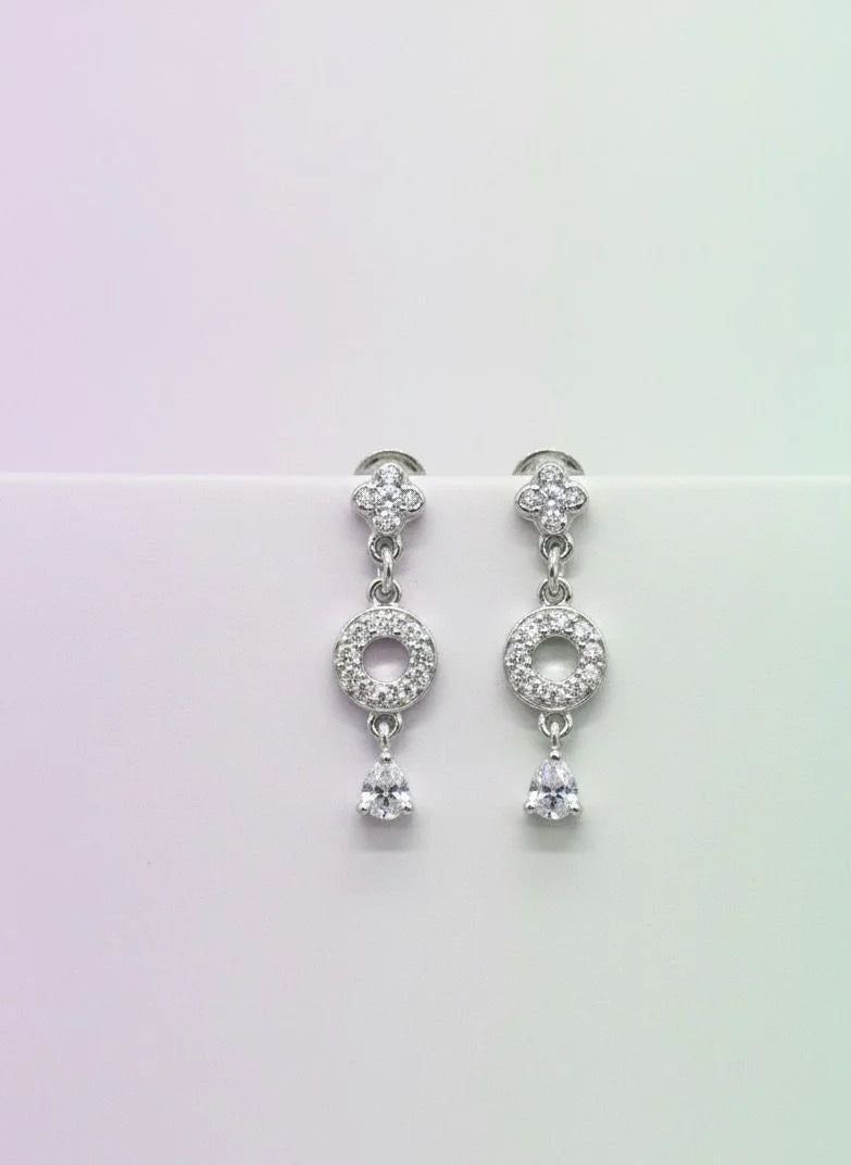 Pair of silver earrings with clear stones on a gradient background