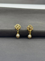 Gold earrings with pearl drops on a gray background