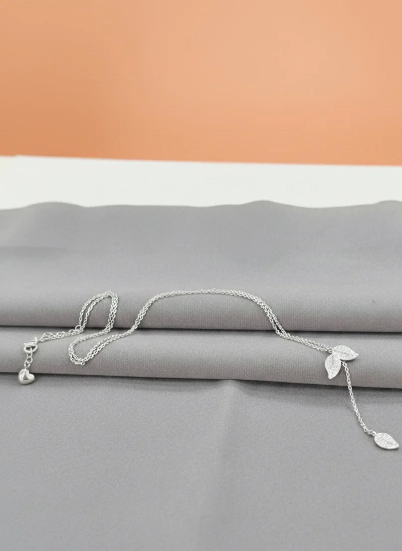 925 Silver necklace with leaf pendants on a gray surface with an orange background