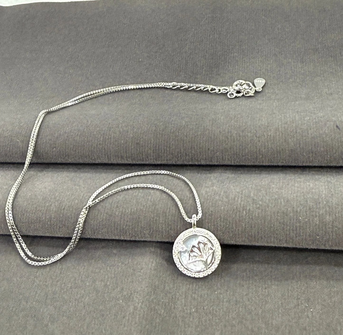 Silver necklace with a round pendant on a gray surface