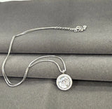 Silver necklace with a round pendant on a gray surface