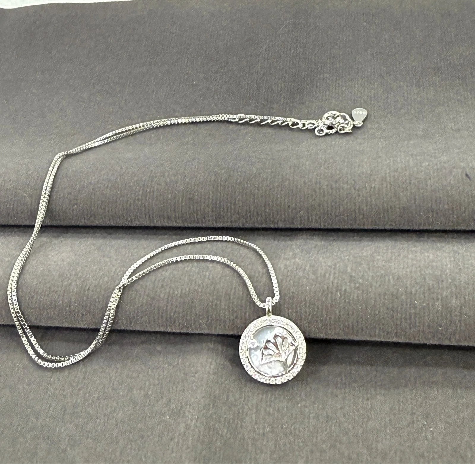 Silver necklace with a round pendant on a gray surface