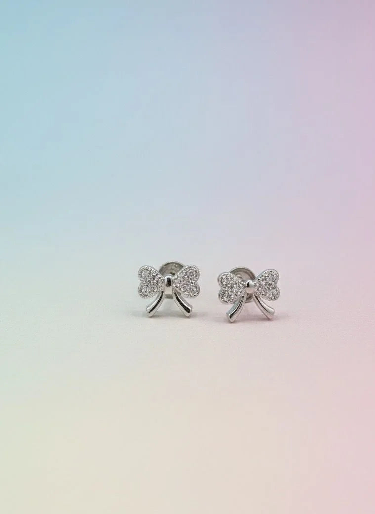 Silver bow-shaped earrings on a gradient background
