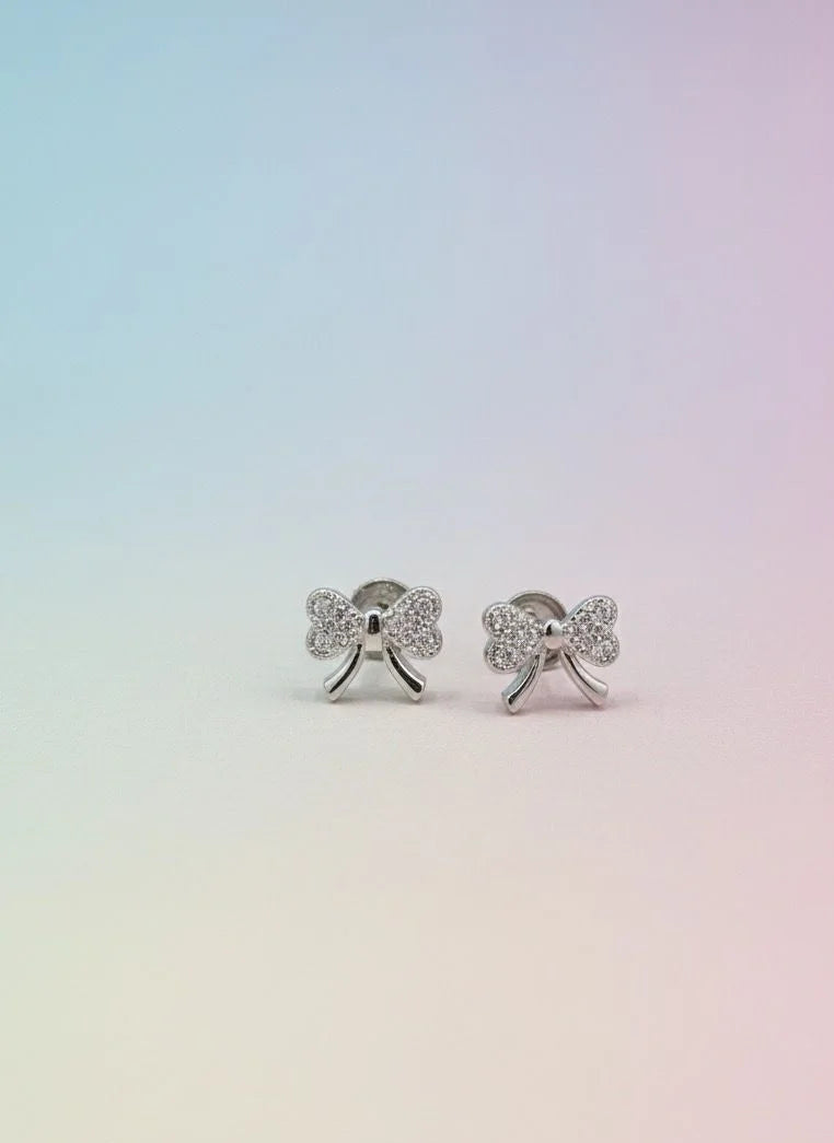 Silver bow-shaped earrings on a gradient background