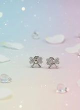 Silver bow-shaped earrings on a soft, gradient background with water droplets.