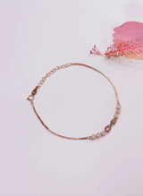 Rose gold bracelet with small stones on a light pink background