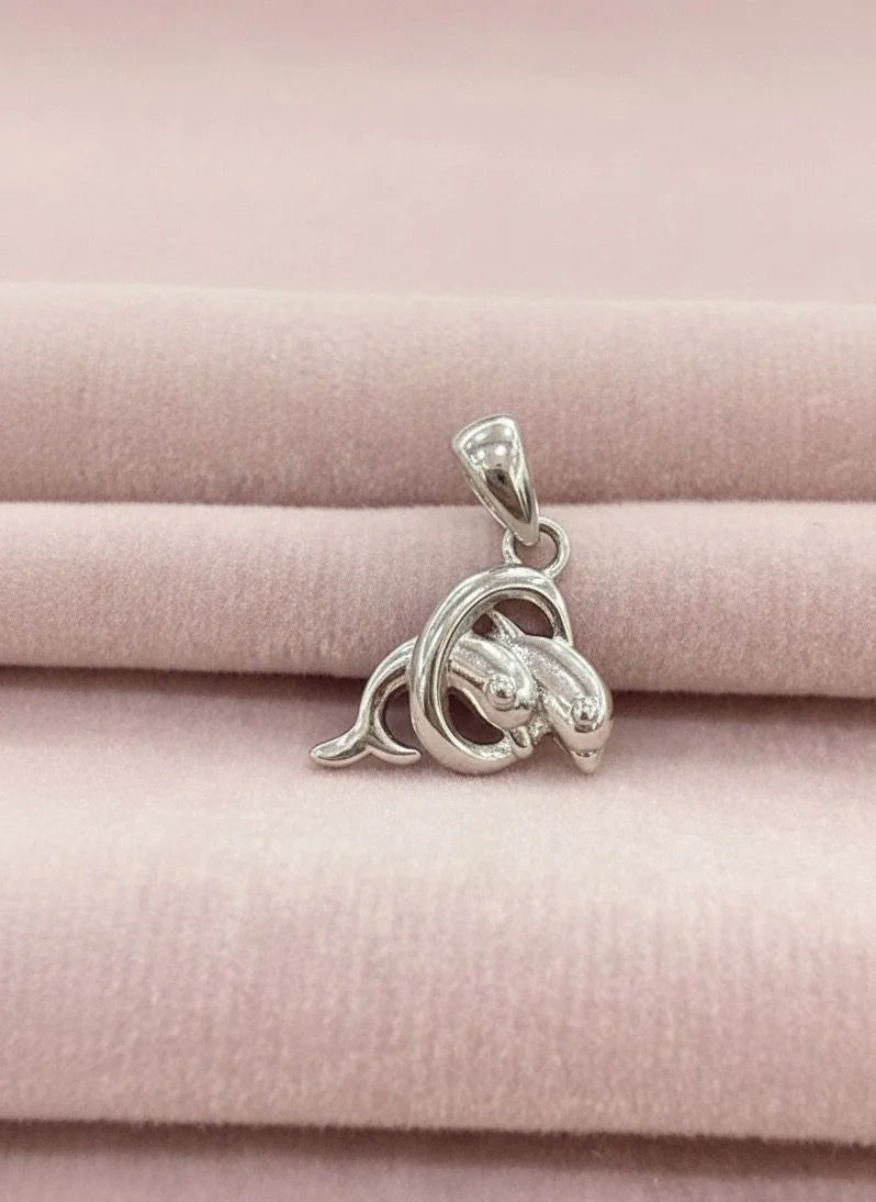 Silver dolphin pendant on a pink fabric background