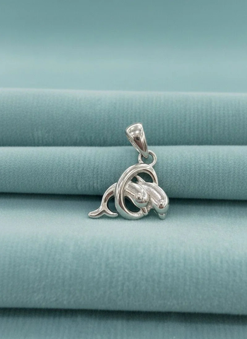 Silver dolphin pendant on a light blue fabric background