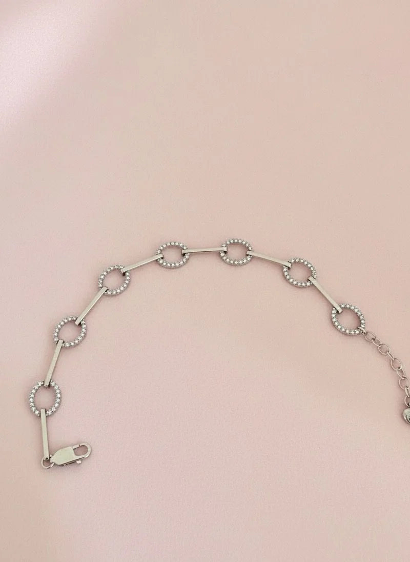 Silver bracelet with circular links on a pink background