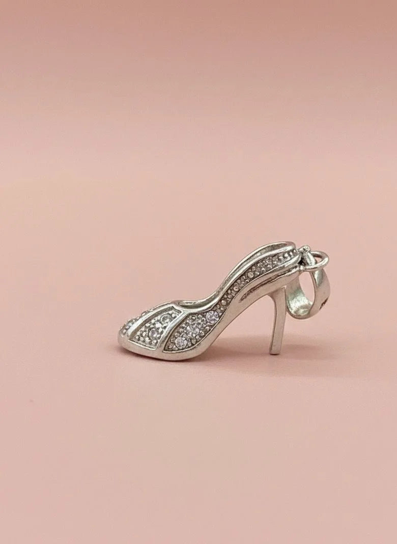 Silver high-heeled shoe charm on a pink background