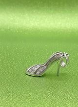 Silver high-heeled shoe charm on a green textured background