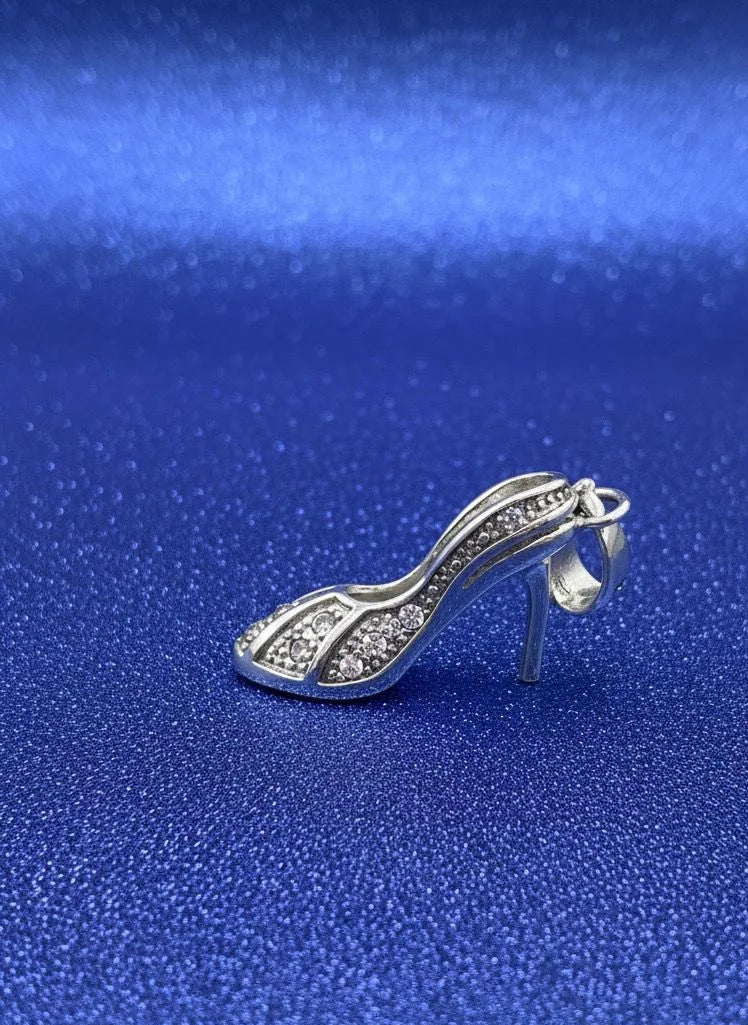 Silver high-heeled shoe charm on a blue textured background