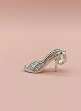Silver high-heeled shoe charm on a pink background