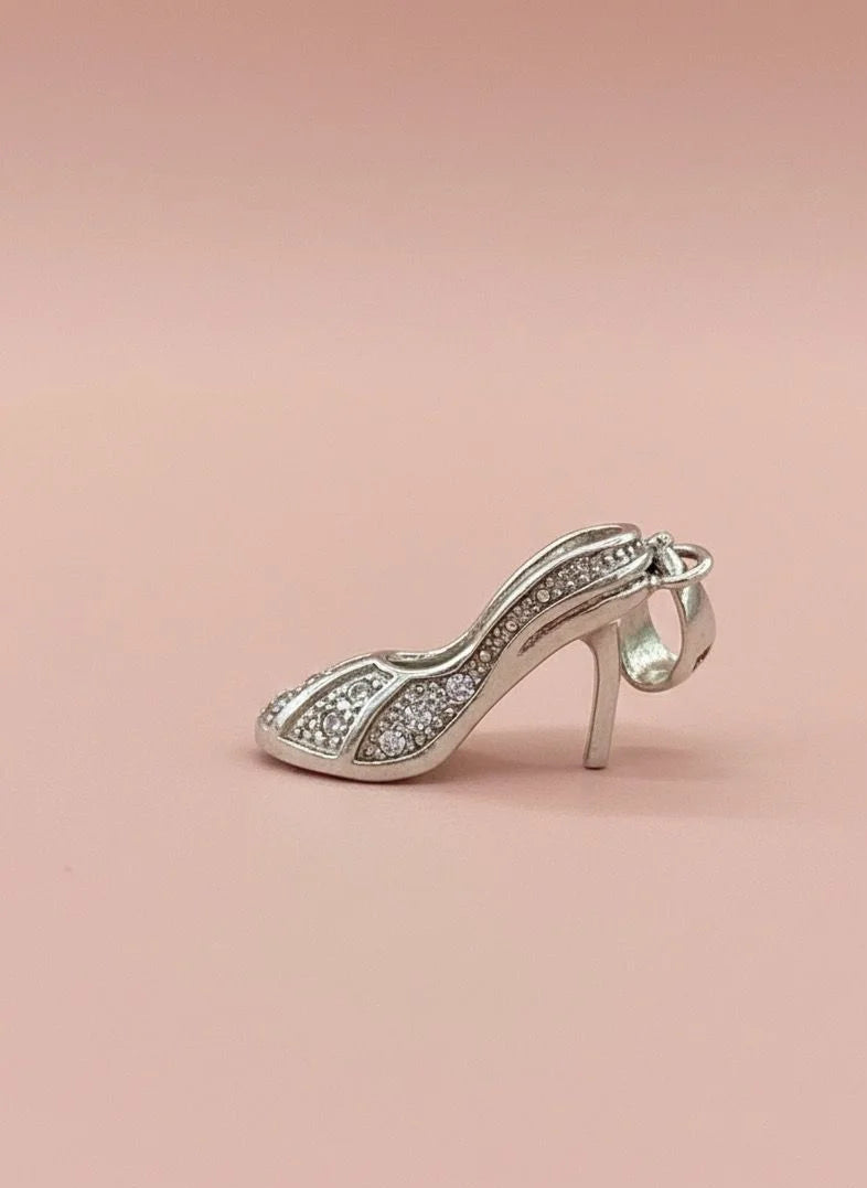 Silver high-heeled shoe charm on a pink background