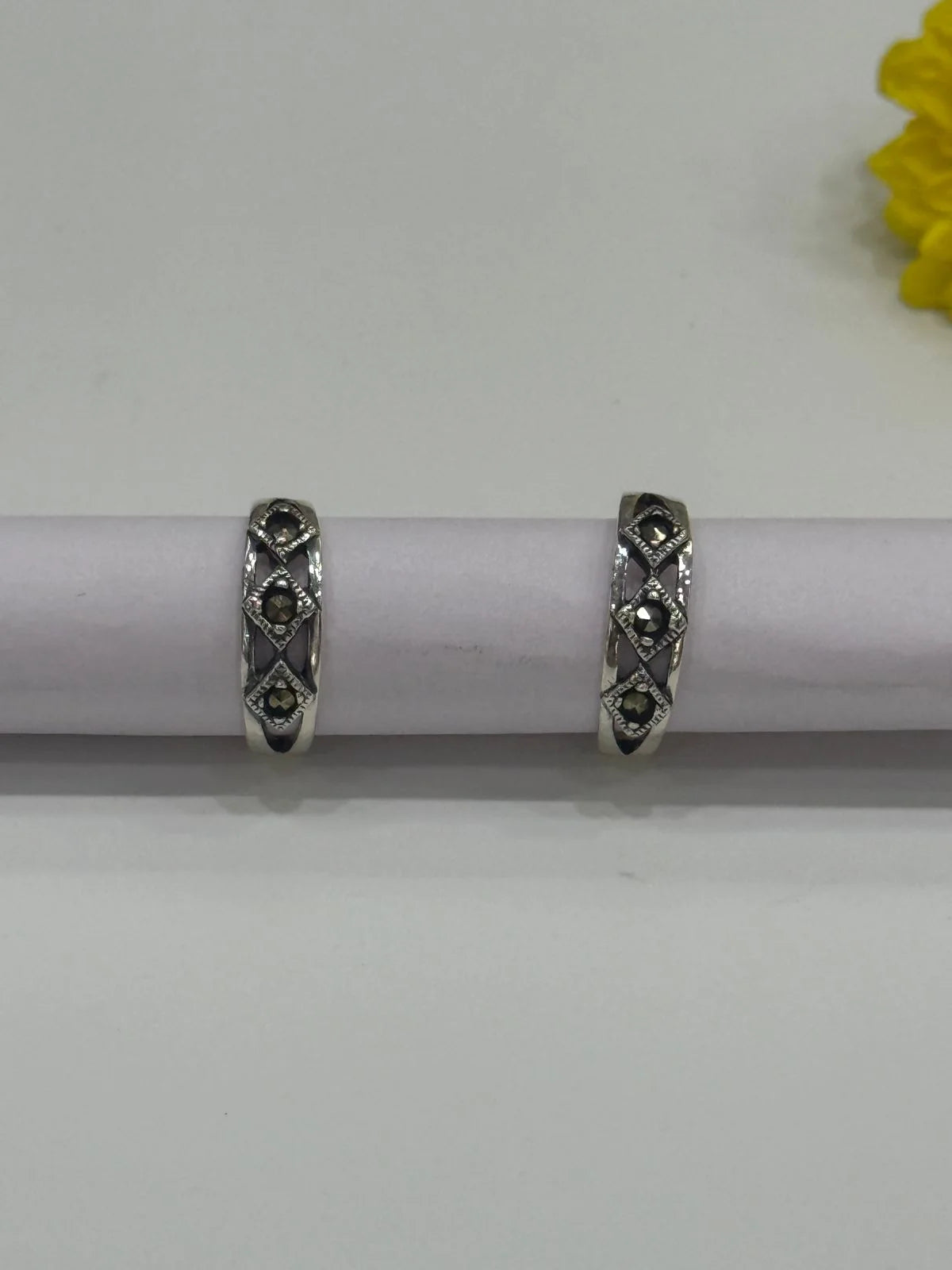 Pair of silver toe rings with black stones on a white background