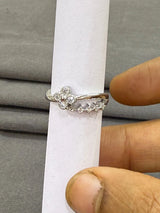 Silver ring with small diamonds held by a hand on a gray background