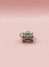 Silver bow-shaped charm on a pink background