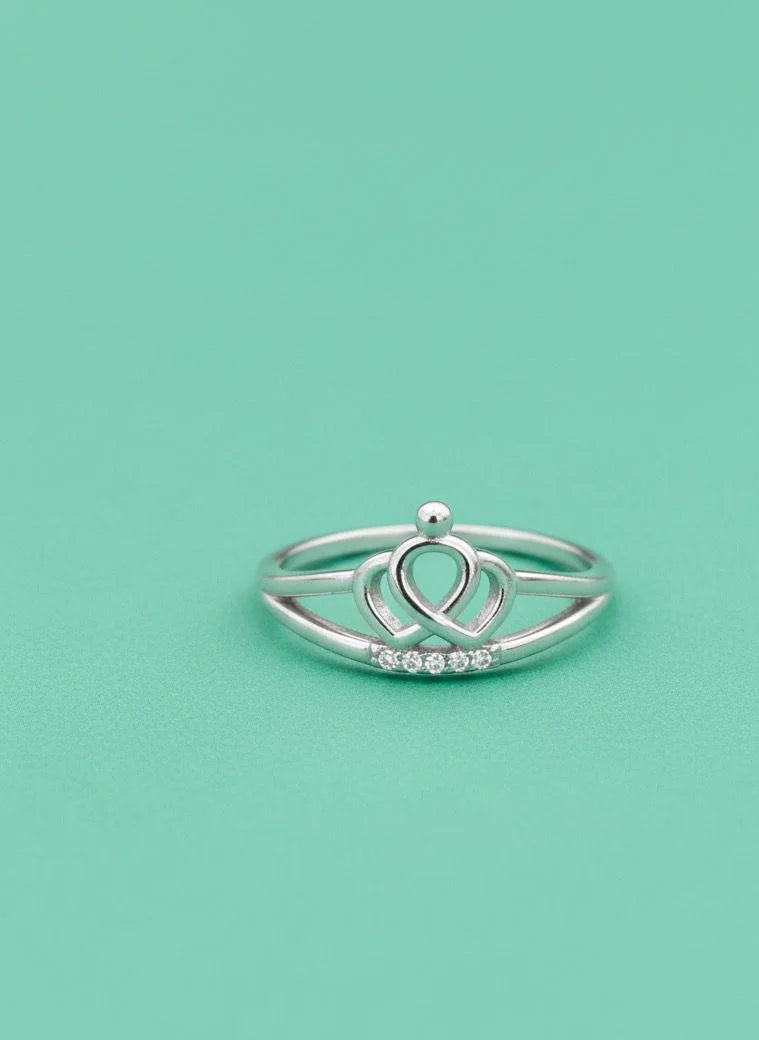 Silver ring with a heart design on a light green background