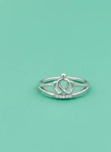 Silver ring with a heart design on a light green background