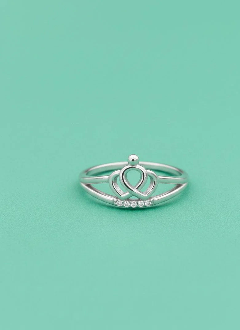 Silver ring with a heart design on a light green background