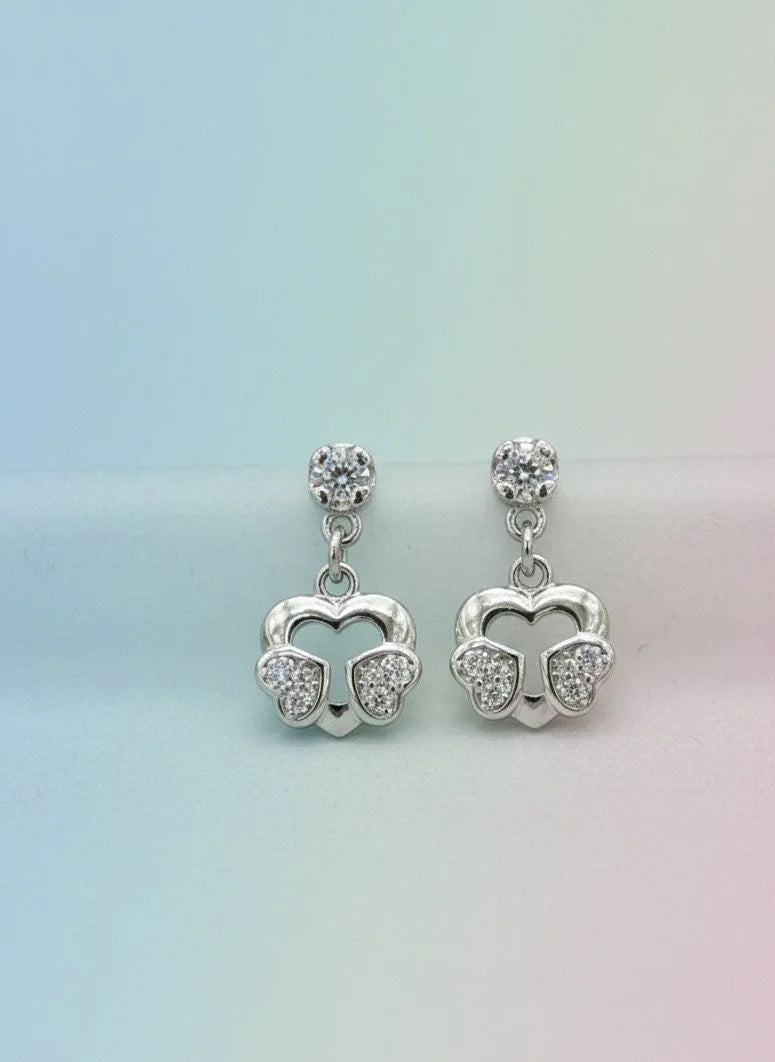 Silver earrings with heart designs on a gradient background
