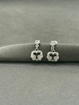 Pair of silver earrings with heart-shaped designs on a gray surface