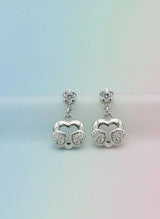 Pair of silver earrings with heart designs on a gradient background