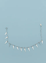Silver bracelet with spike-like hangings on a light blue background