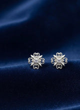 Silver floral earrings on a blue fabric background