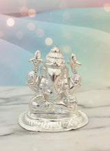 Silver Ganesha statue on a marble surface with a blurred light background