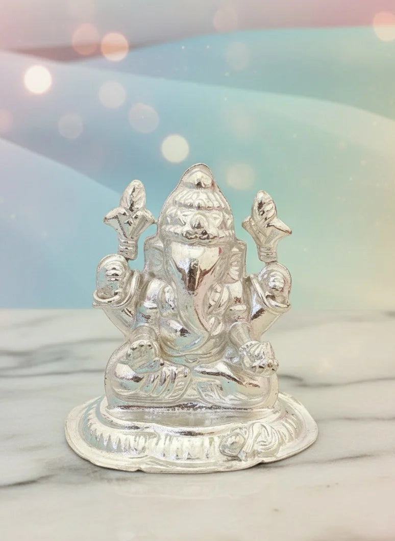 Silver Ganesha statue on a marble surface with a blurred light background