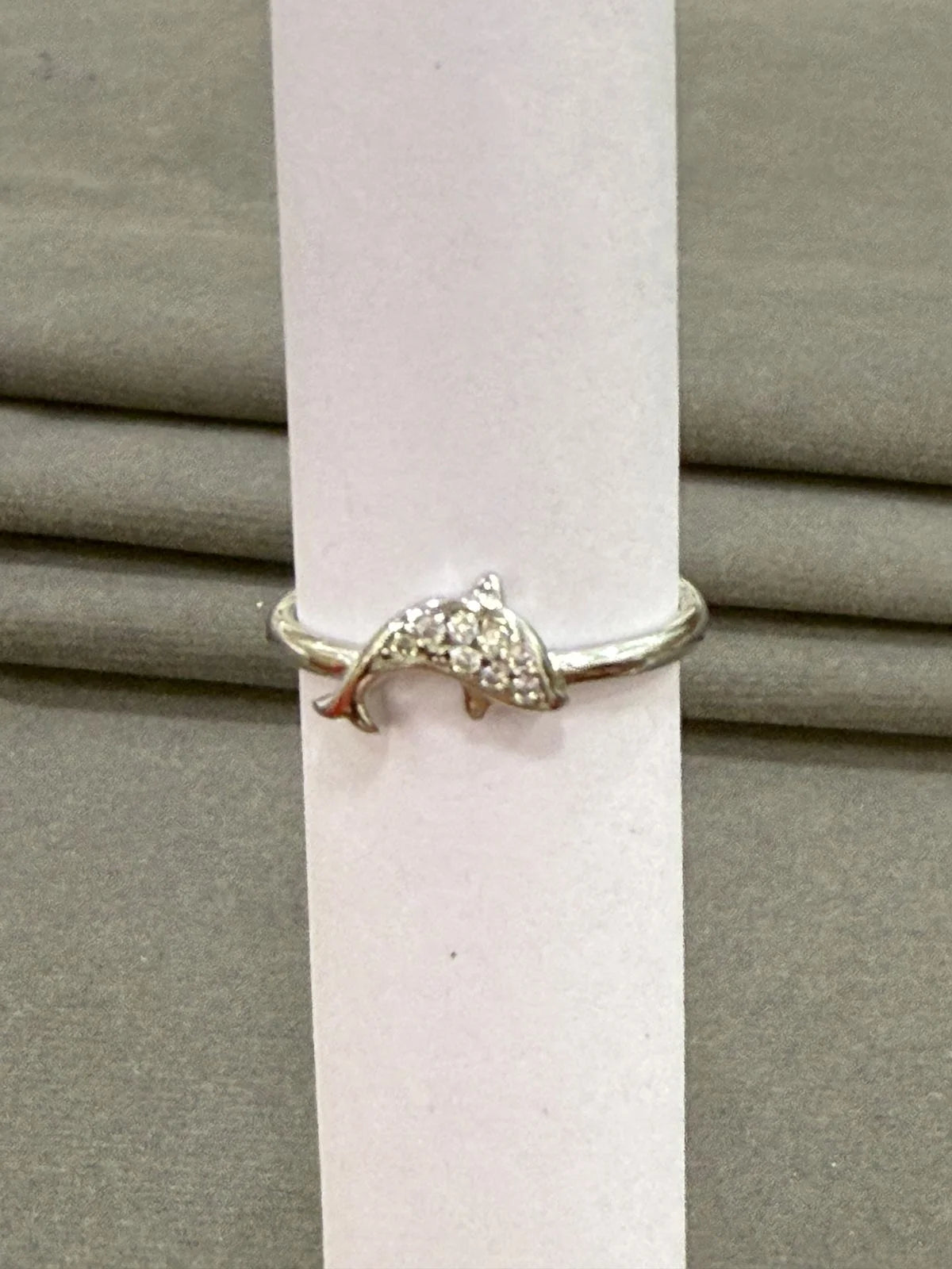 Silver dolphin ring on a white candle against a gray background