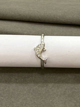 Silver ring with a dolphin design on a white cylindrical object against a gray background