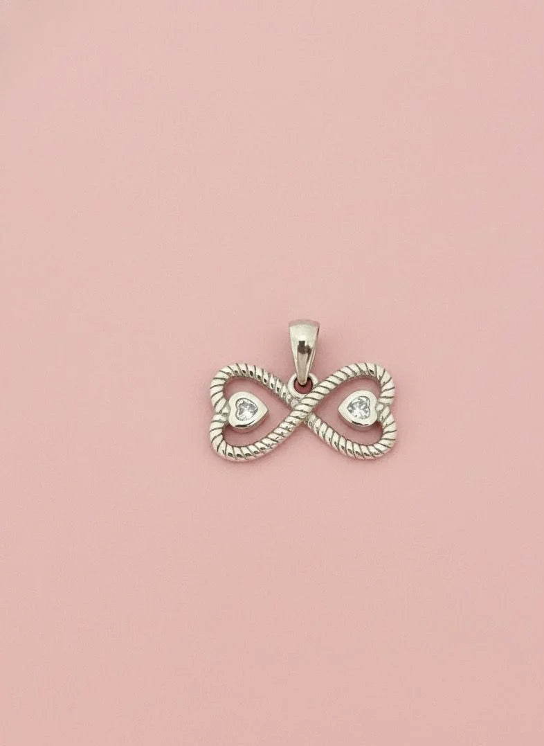 Silver infinity pendant with heart cutouts on a pink background