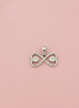 Silver infinity pendant with heart cutouts on a pink background