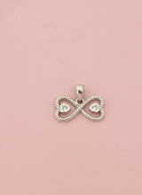 Silver infinity pendant with heart cutouts on a pink background
