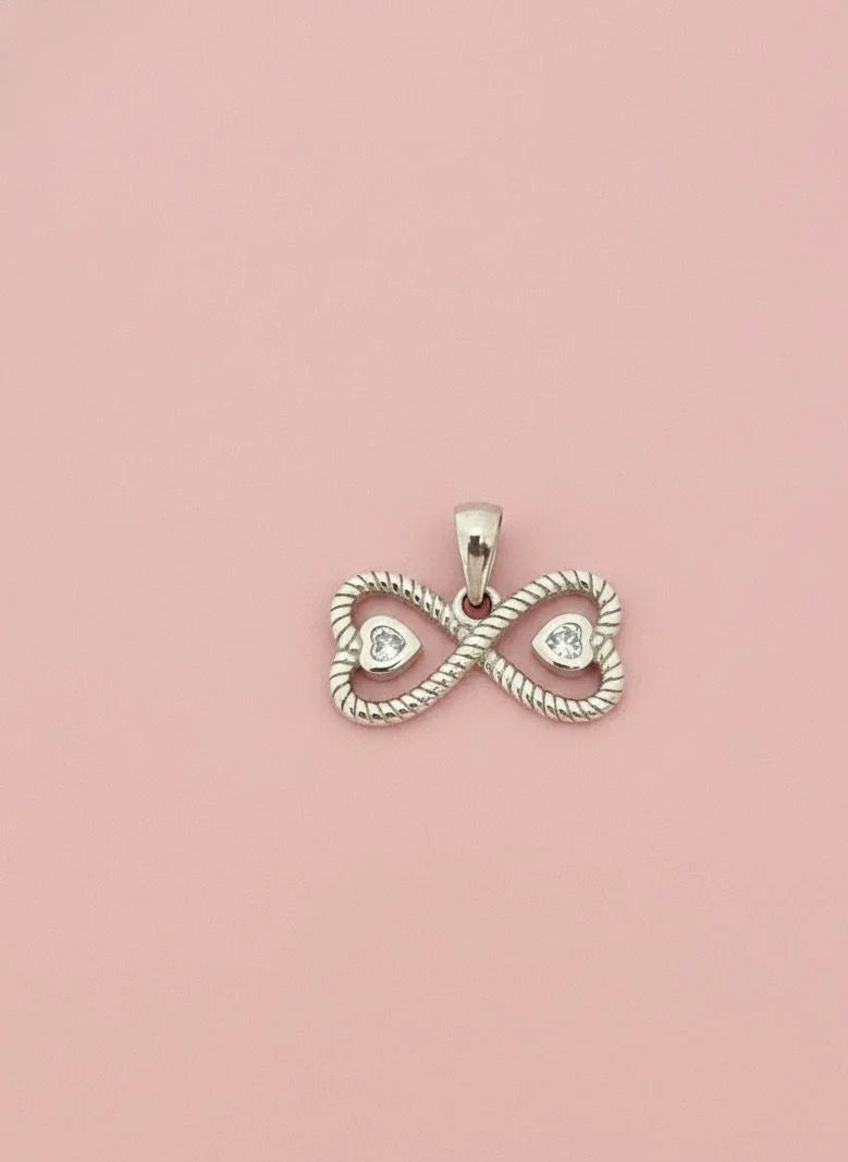 Silver infinity pendant with heart cutouts on a pink background