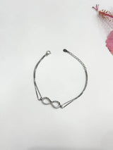 Silver infinity bracelet on a light gray background