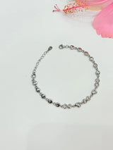 Silver bracelet on a light gray background with pink floral elements