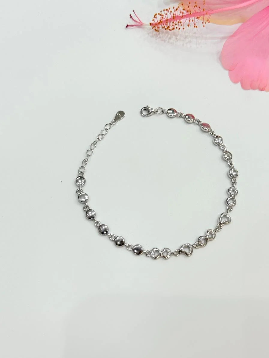 Silver bracelet on a light gray background with pink floral elements